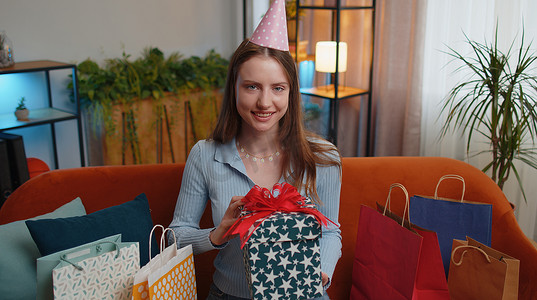 快乐的年轻女人拿着带丝带的生日礼盒，庆祝派对，在家开礼物