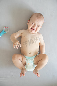 孩子生气摄影照片_床上哭闹的婴儿的肖像