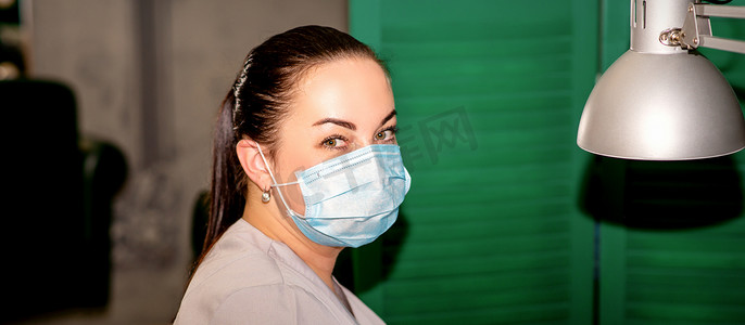足科摄影照片_戴着防护面罩的年轻女足病医生在她的足病诊所里看着镜头。