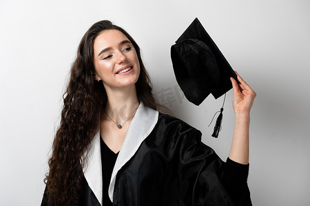 拥有硕士学位的研究生女孩，穿着黑色毕业礼服，戴着白色背景的帽子。