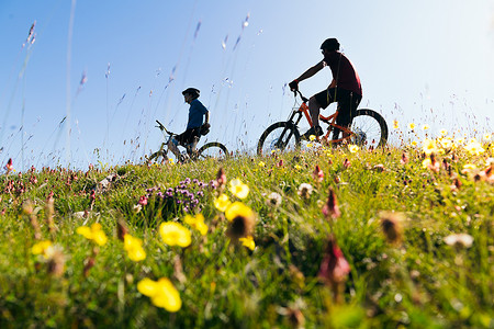 两个年轻朋友在草地上骑山地自行车
