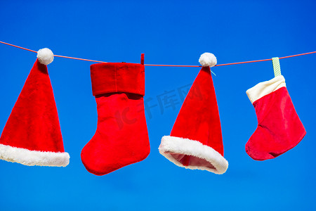 红色圣诞老人帽子和圣诞袜挂背景蓝天