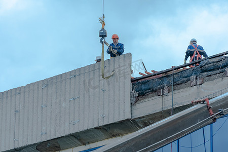 莫斯科，俄罗斯，05,10,2021：建筑物的修复、重建和维修。戴安全帽的建筑工人在结构的屋顶上安装混凝土板。房屋修复施工