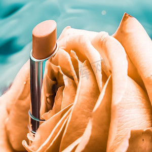 液体背景中的黄色口红和玫瑰花、防水魅力化妆品和唇彩化妆品产品，适用于豪华美容品牌假日设计