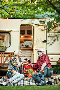 快乐的老年男女在露营车附近野餐时聊天