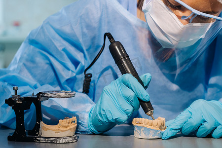 一名身穿防护服的牙科技师正在他的实验室研究假牙
