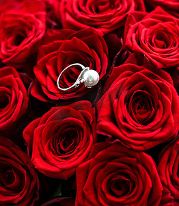 美丽的白金珍珠戒指和红玫瑰花束，情人节和浪漫假期的奢华珠宝爱情礼物
