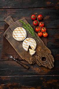 旧深色木桌背景上的烤卡门培尔奶酪或布里干酪，顶视图平躺，带有文本复制空间