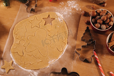 康乃馨手工摄影照片_在木桌上烹饪圣诞饼干的生面团的顶部视图。