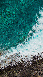 海洋波浪摄影照片_绿松石波浪和上面的海泡沫中的石头。