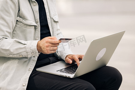 支付验证摄影照片_特写视图持卡人持有信用卡进行电子银行在线支付的男性手。