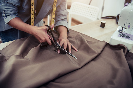线裁缝摄影照片_裁缝用缝纫机在草图线上裁剪礼服面料。