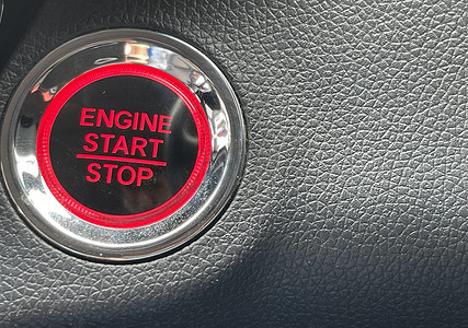 汽车发动机启动停止按钮在深色皮革背景上。