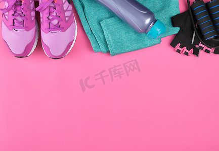 粉色女式运动鞋、一瓶水、手套和跳绳