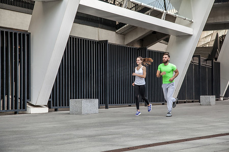 在城市环境中跑步的夫妇的侧视图。