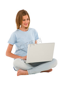 盘腿坐的女孩摄影照片_使用笔记本电脑的十几岁的女孩