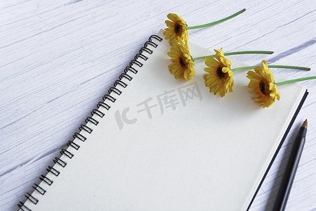 笔记本平铺在木桌上，上面有向日葵。