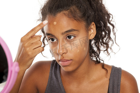 深色皮肤的女人在脸上涂抹粉底液