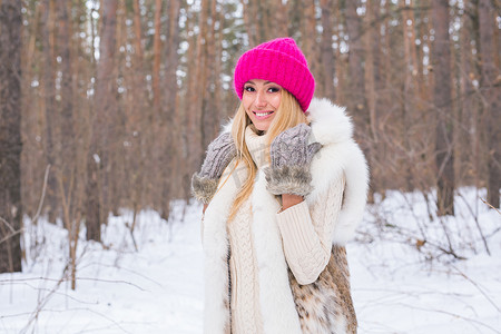 美丽、冬天和人的概念 — 在白雪皑皑的森林里，穿着粉色毛衣的金发美女微笑着