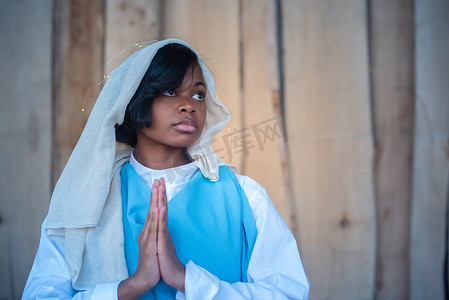 耶稣祈祷摄影照片_黑人圣母玛利亚代表在婴儿床上祈祷