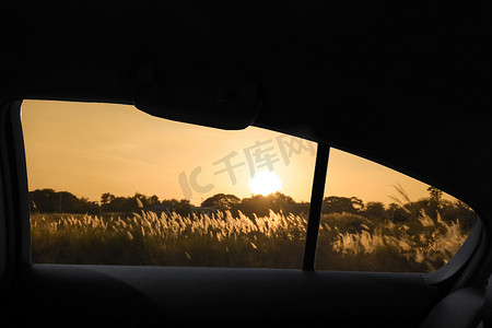 透过车窗看日落时的山地景观和草地野草。
