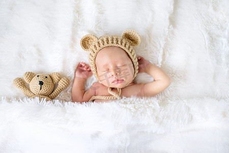 刚出生的婴儿抱着泰迪熊睡觉。