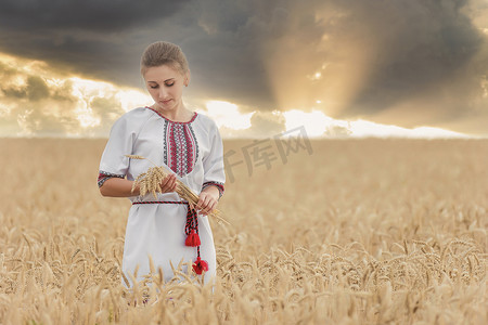爱国主义背景摄影照片_夕阳的天空背景下，手里拿着小麦的女孩