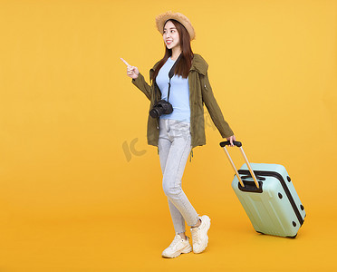 快乐的年轻女子，带着行李和相机，在黄色背景、秋天、旅行概念中被隔离。