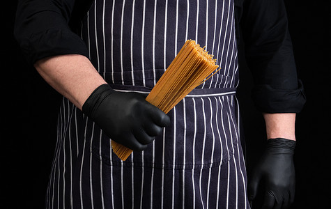 戴着黑色乳胶手套的厨师，条纹围裙拿着生长黄色