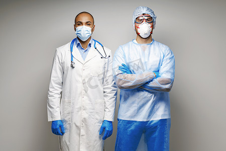 身穿医用制服、戴着口罩站在灰色背景下的男医生