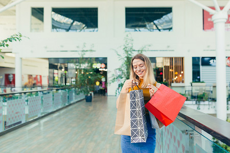 快乐的年轻购物狂女人拿着纸袋购物，面带微笑