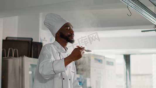 上品气度摄影照片_非裔美国厨师在炉子上品尝蔬菜汤