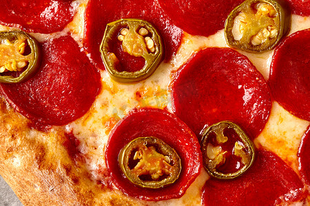 意大利辣味香肠摄影照片_辣披萨特写镜头用意大利辣味香肠、番茄酱、马苏里拉奶酪和墨西哥辣椒