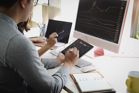 投资专家用笔指着电脑显示器分析股市，教你如何获利。