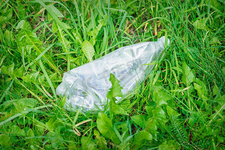 躺在绿草中的皱巴巴的塑料瓶