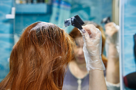 一个女人把头发染成红色，用指甲花或染料给发根上色