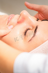 美容师在美容院进行淋巴引流面部按摩或整容按摩。
