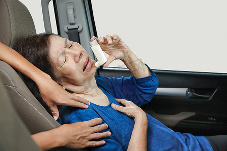 手拿喷雾摄影照片_老妇在路上拿着哮喘喷雾在车内窒息