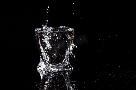 黑色背景是一个玻璃杯，其中有一滴水落下。