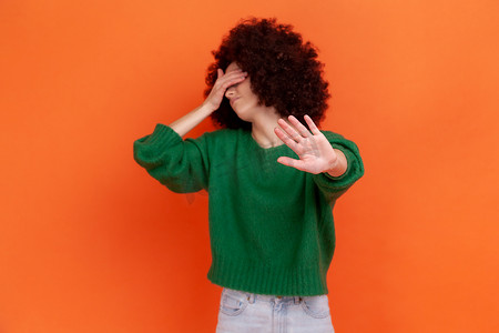 涉酒禁令摄影照片_沮丧的非洲发型女人穿着绿色休闲风格的毛衣，用手掌遮住眼睛，并用手掌表现出停止禁令的手势。