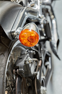 公路指示灯摄影照片_闪亮的黑色摩托车上有橙色转向灯、信号灯和指示灯。