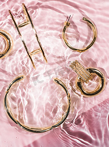 金手镯、耳环、戒指、粉色水背景的珠宝、奢华魅力和珠宝品牌广告的假日美容设计