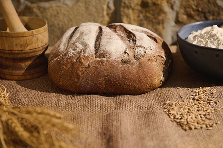 bre摄影照片_粗麻布桌布上自制新鲜烘焙小麦面包、小麦小穗和烘焙配料的食品组合物