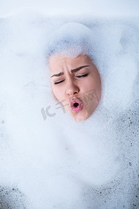 一个女孩在浴缸里的特写肖像和她脸上的白色泡沫。