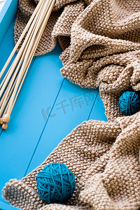 线团png摄影照片_木针位于蓝色背景上明亮的线团和针织毯旁边