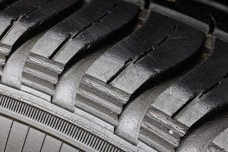 车轮磨损摄影照片_旧磨损的黑色轮胎，车轮上有许多大裂缝。