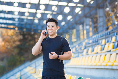 培训分享摄影照片_成功的亚洲男运动员通过电话交谈，分享他的运动成就