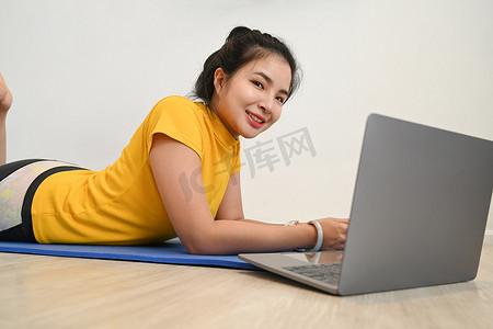 亚洲女性在客厅锻炼并在笔记本电脑上观看在线教程
