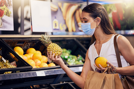 在商店购物、拿着和看水果、在杂货店戴口罩以确保安全并防止感染新冠病毒。