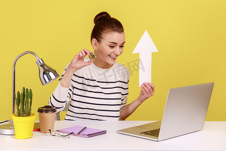 一位女士向笔记本电脑屏幕展示比特币和白皮书箭头，显示加密货币的增长。